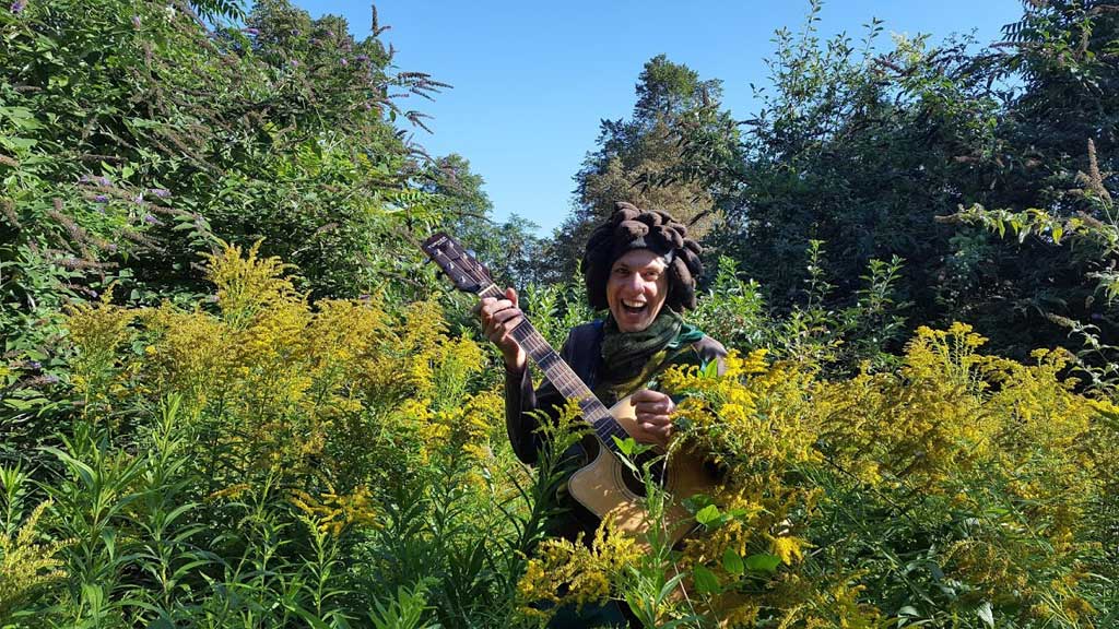 Photo of person with guitar in a bush