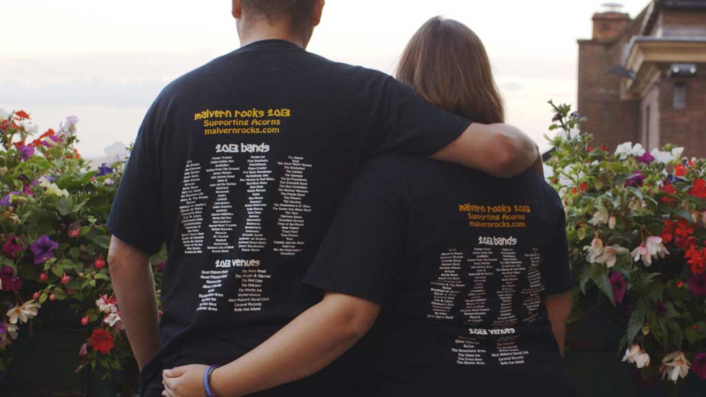 Photo of backs of three Malvern Rocks t-shirts