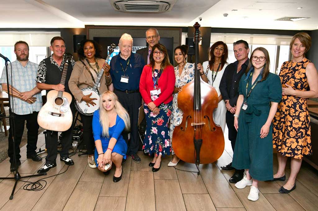 Photo of Jim Simpson 5th from left with speakers and Hit Parade Heroes at Jazz Festival launch